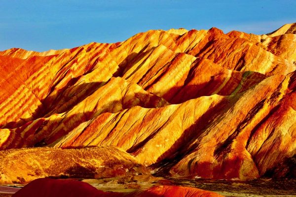 Brilliant red, orange and yellow hues inform this image of an imposing mountain range in Gansu Province, China.