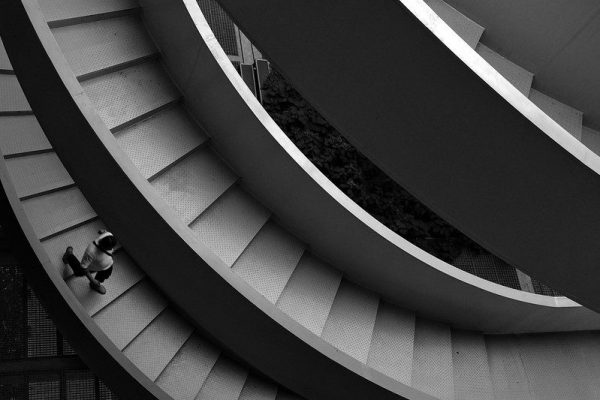 A person, seen from above, walks down a spiral staircase