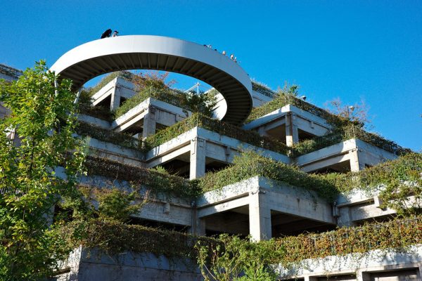 People look out from a round walkway at the top of a series of angular stepped terraces