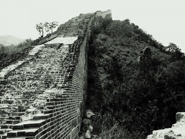 A series of narrow, crumbling brick stairs climb steeply up a hillside in this black and white image of an ancient, crumbling section of the Great Wall known as Huanghuacheng (located in Jiuduhe Village, Huairou District, Beijing).