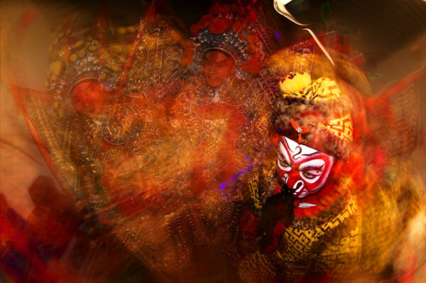 A stylized “Peking Opera backstage” photo shows a performer in an elaborate yellow costume and the red-and-white face make-up of the Monkey King, and the superimposed visages of two other performers wearing elaborate costumes and headdresses.